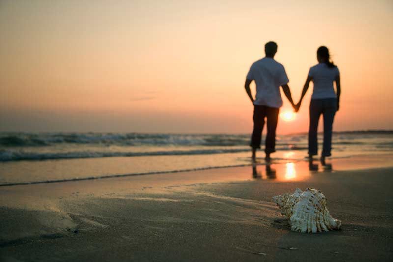 two people walking on a beach hand and hand